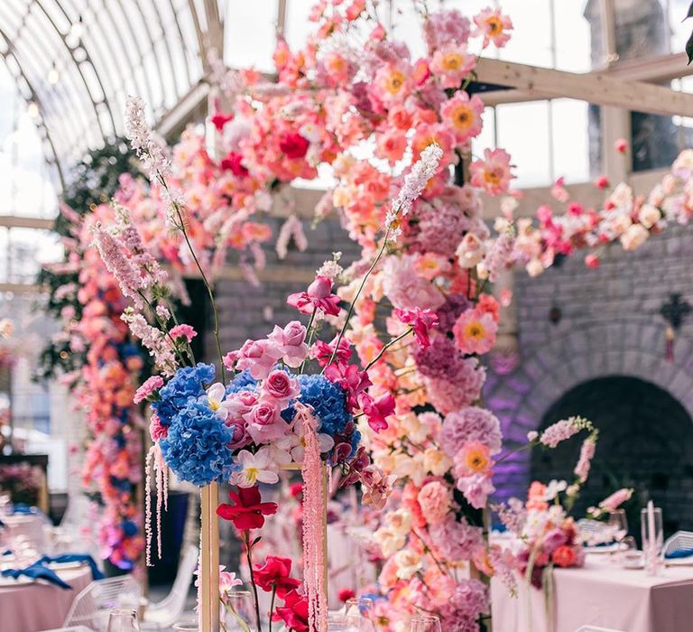 Botanical wedding with incredible wedding table centrepieces made up of blue, pink, and red wedding flowers 