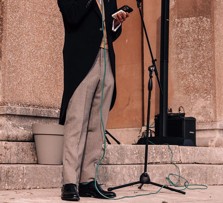 The groom in a morning suit wearing a yellow tie and blue waistcoat reads out his groom speech 