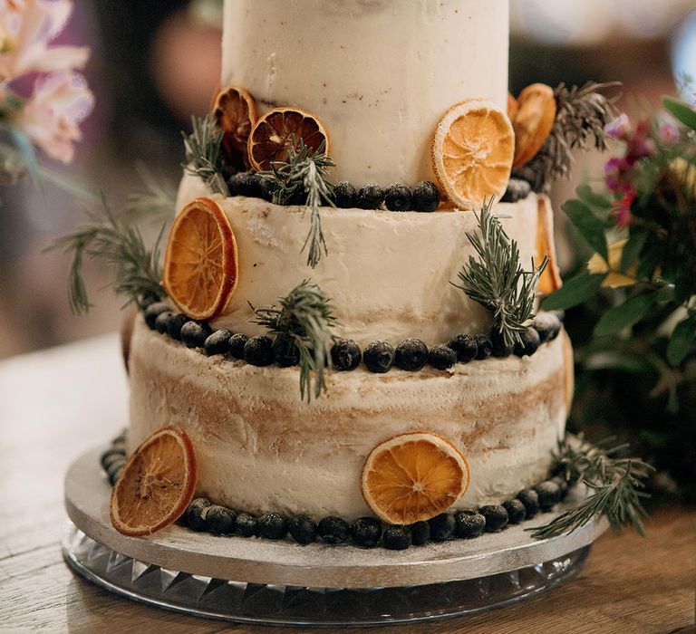 Three tier rustic wedding cake decorated with dried orange slices and blueberries for spring wedding 