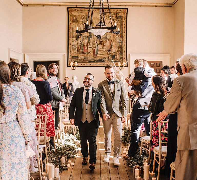 The two grooms walk back down the aisle together at their big day 