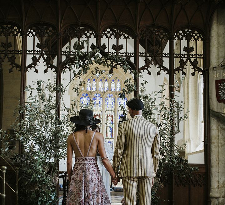 Bride in Pink Rue De Seine boho Wedding dress stands at altar with groom in mustard pinstripe suit at church ceremony