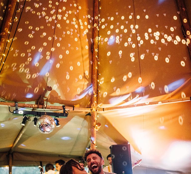 Tipi wedding reception with the bride and groom having their first dance with a giant disco ball