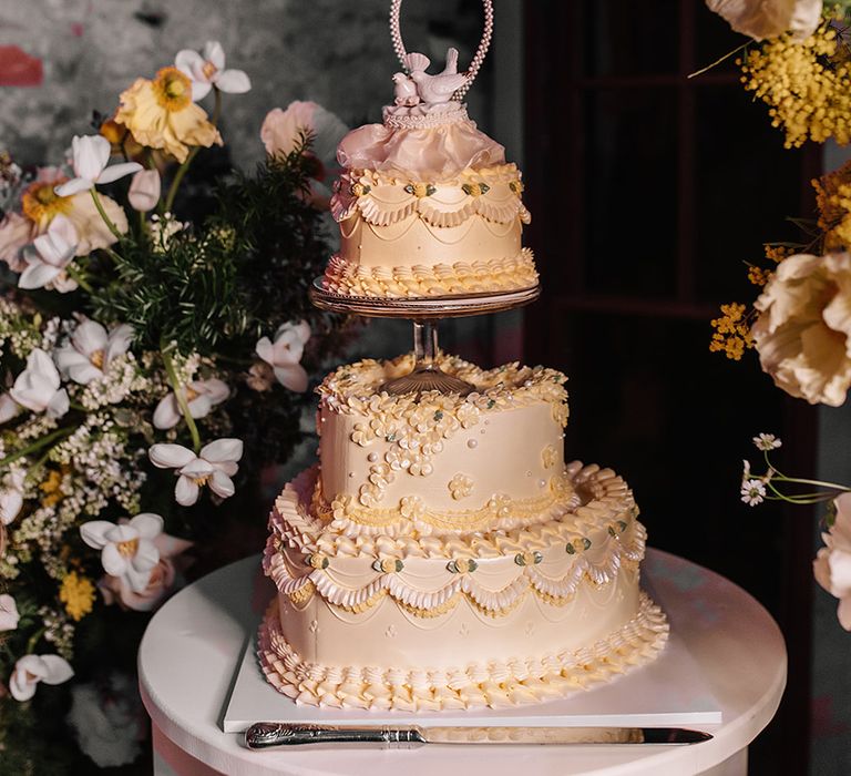 Heart shaped yellow retro wedding cake with dove cake toppers 