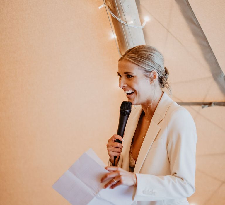 The bride in a white wedding suit reads out wedding speech 