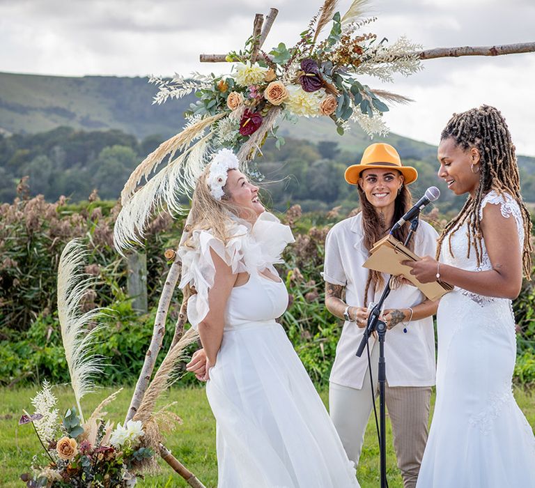 The brides exchange wedding vows at their outdoor wedding ceremony 