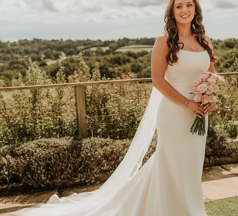 Bride in satin slip wedding dress holding pink rose wedding bouquet for at home wedding 