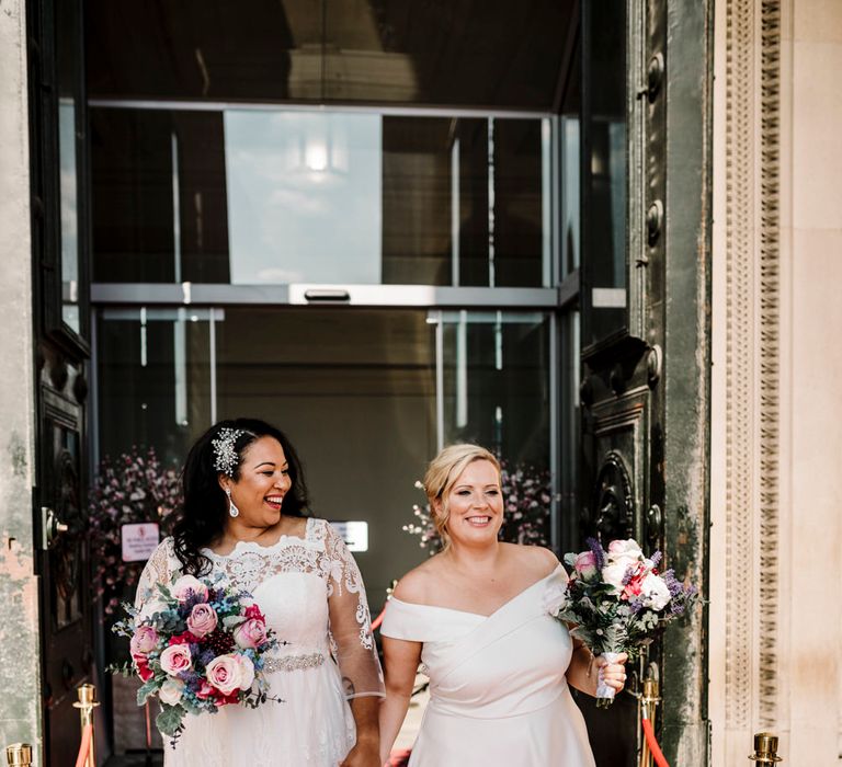 Newly wed lesbian brides with pink and white rose bouquets 