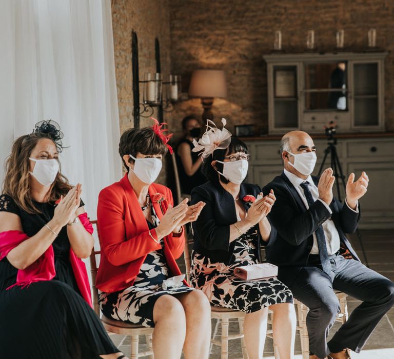 Wedding guests wearing facemasks clapping