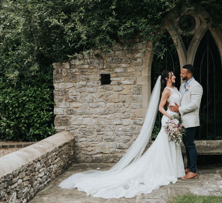 Bride wears Christina Wu dress with long train in couples portrait shoot at The Tythe Barn