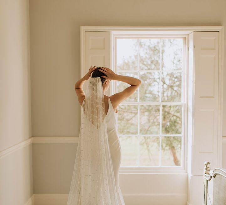 Bride looking out of the window at Reymerston Hall 