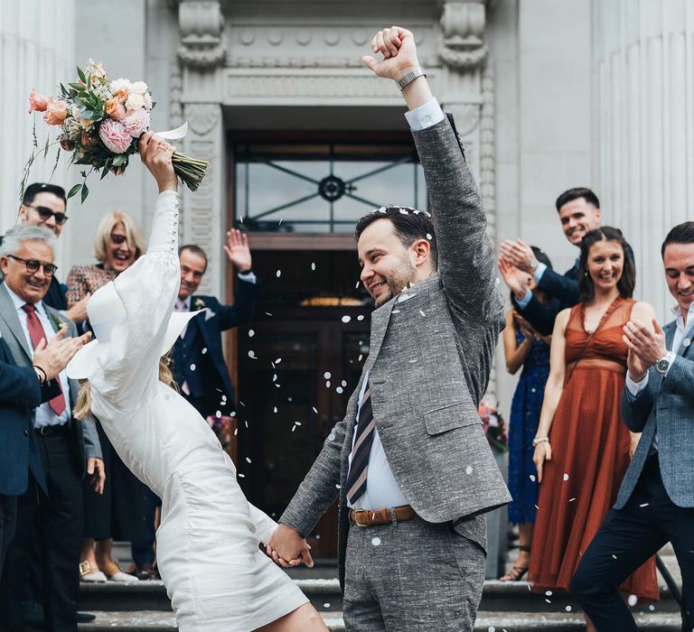 Bride and groom celebrating with arms up in celebration 