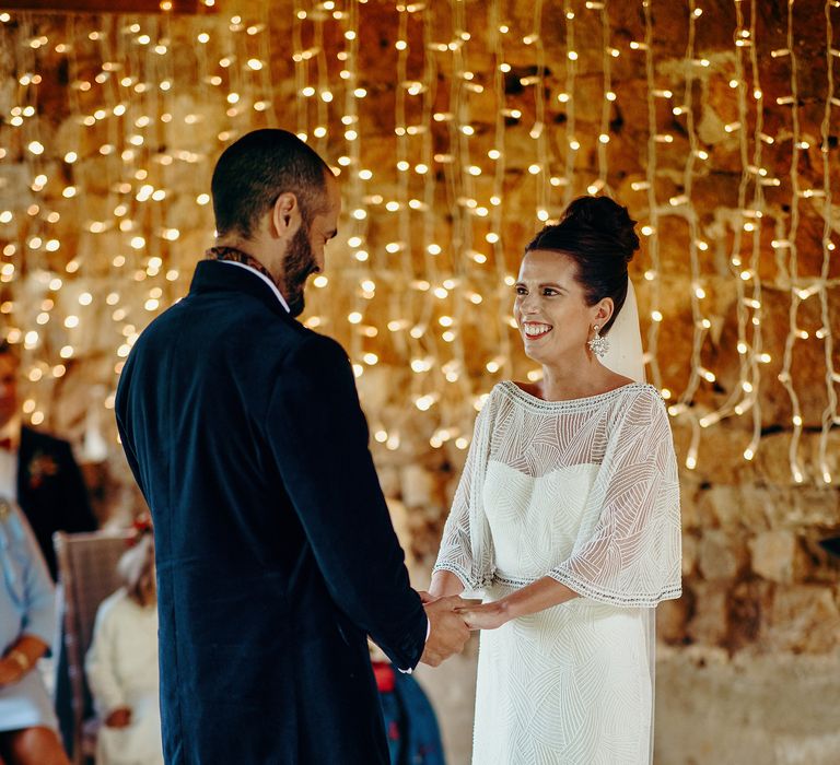 Bride & groom say their vows with fairy lights curtain in background