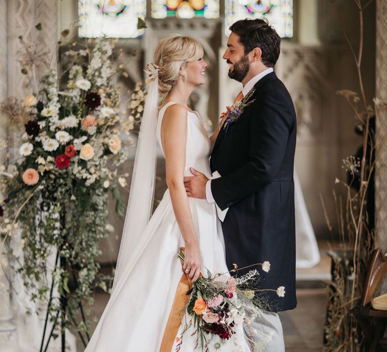 Bride and groom standing at the altar with wildflower wedding arrangements 