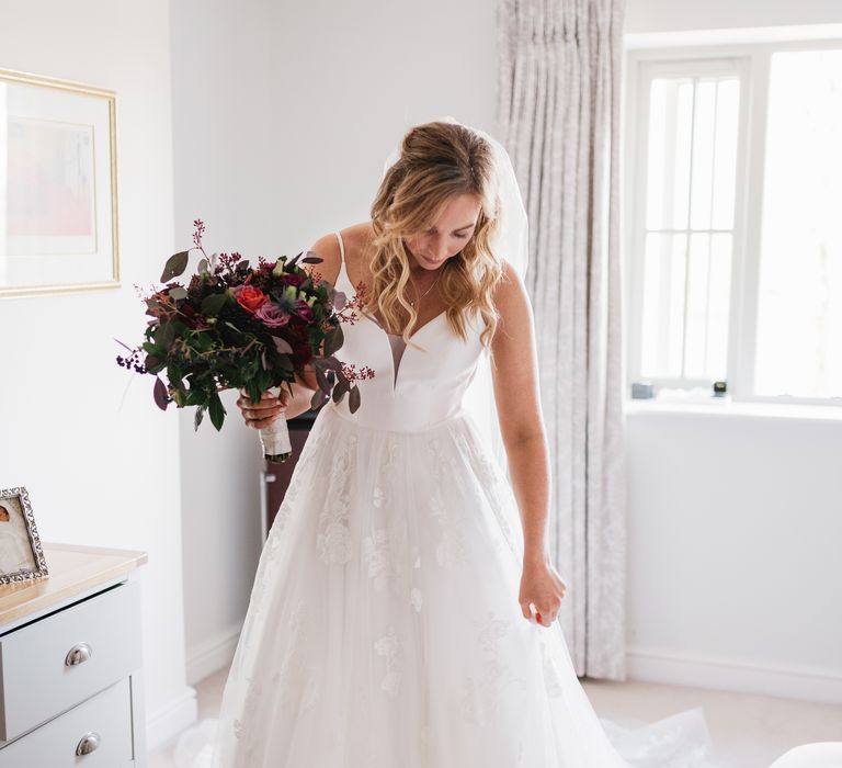 Bride stands in her wedding gown holding pink floral bouquet