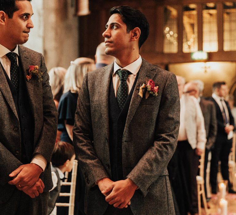 Groom waiting at the altar with the best man in a grey wool suit with green tie and navy waistcoat