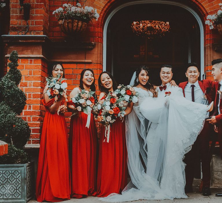 Bride & groom stand with wedding party in red and gold wedding 