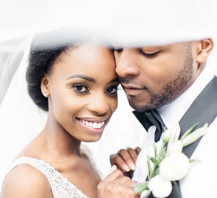 Bride & groom pose for photo under brides veil