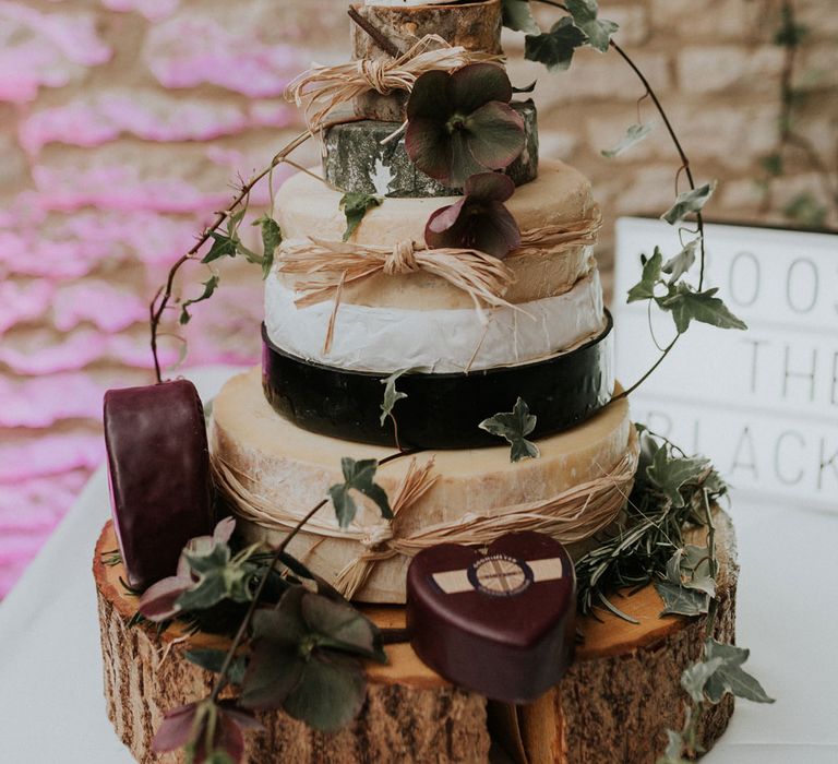 Cheese round tower on rustic bark serving board with foliage decor at Caswell House wedding