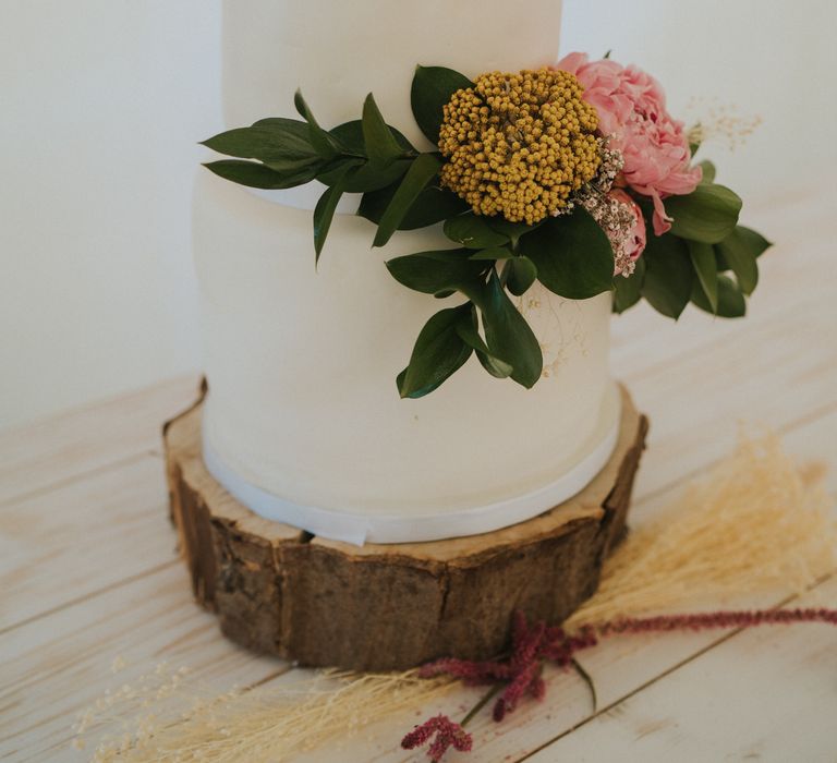 Two-tier wedding cake with white frosting and floral decor