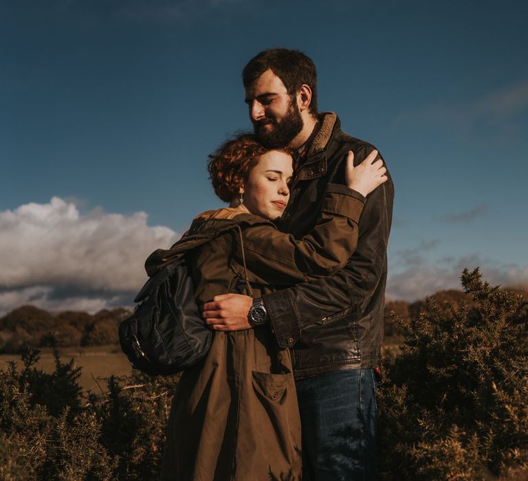 Bride-to-be leans her head on the chest of her future husband outdoors