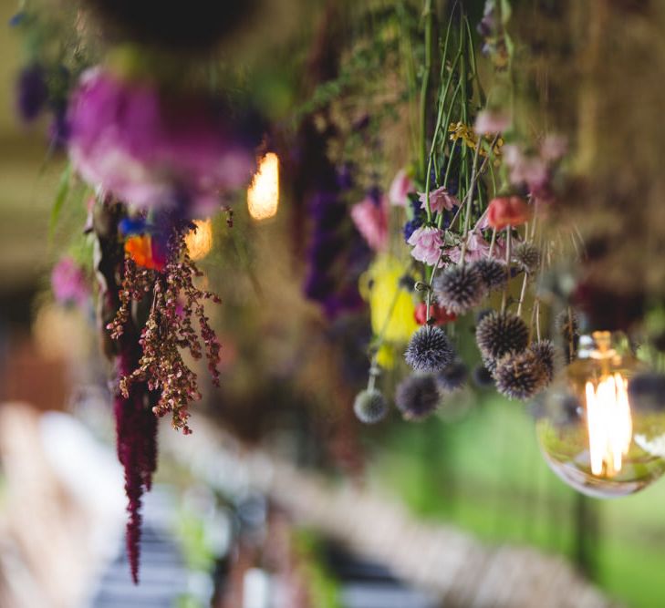 Hanging bunches of flowers and Edison bulb over banquet tables - Image courtesy of Marble Private