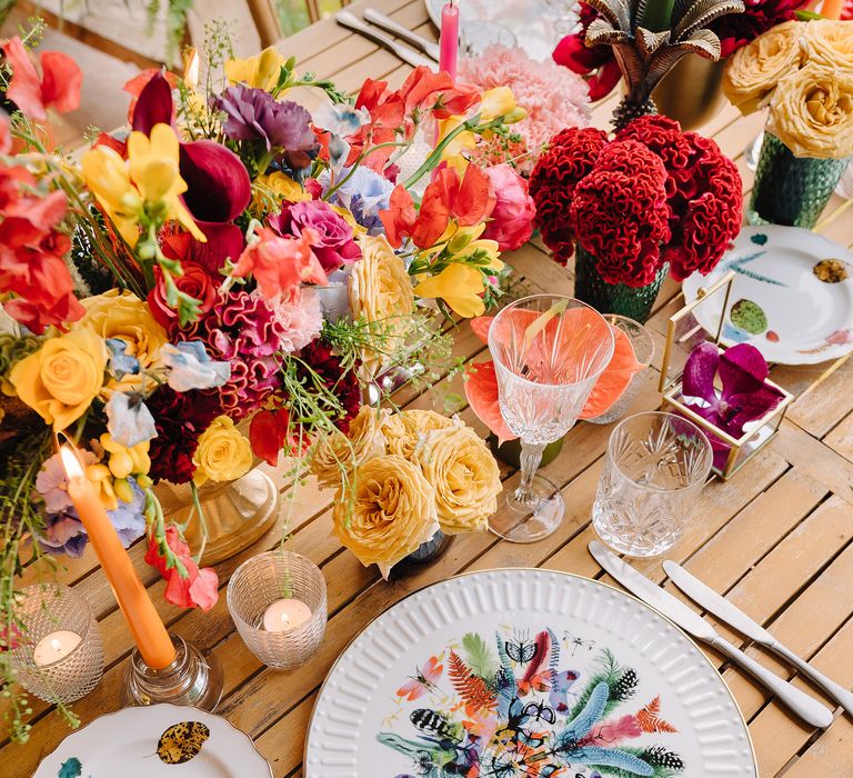 White plates with colourful print and bright floral bouquets lining table