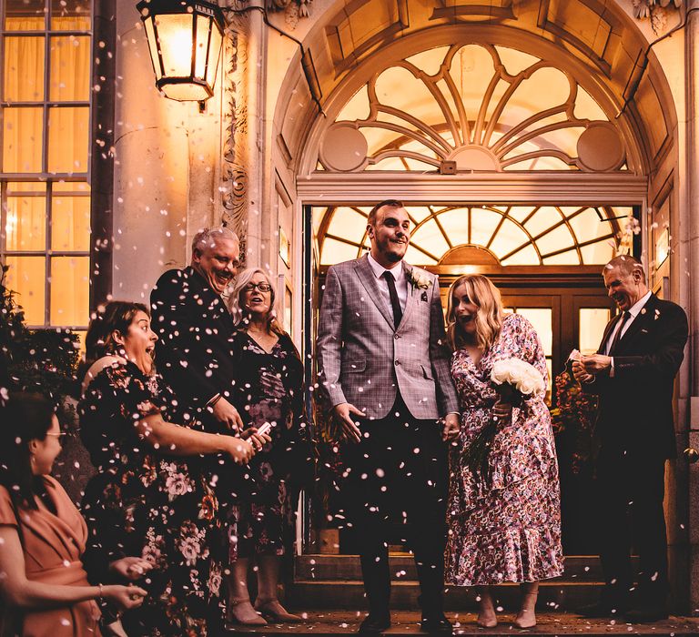 Bride & groom have confetti throw around them by wedding party after Town Hall wedding