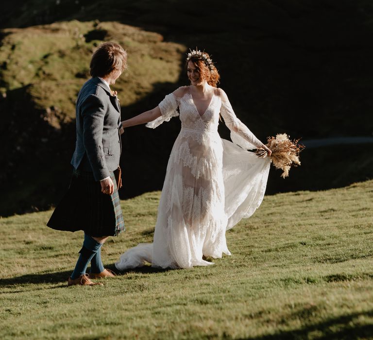 Bride leads groom along hillside together