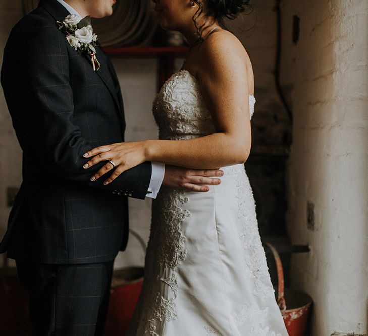 Close up of a bride in Sophia Tolli and groom as they hold each others waists.