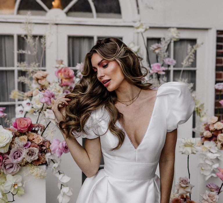 Beautiful bride with long wavy hair in a taffeta wedding dress with plunging neckline 