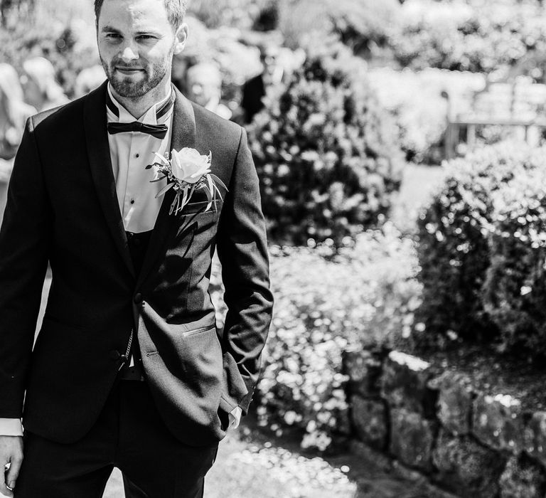 Black & white image of groom wearing tux waiting for bride on his wedding day