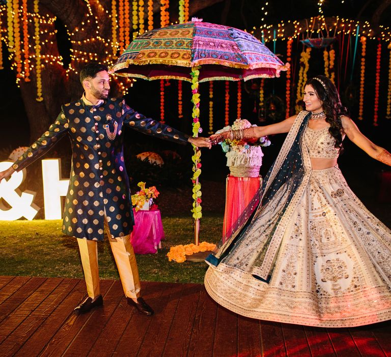 Bride & groom dance during Sangeet night outdoors surrounded by light up personalised letters