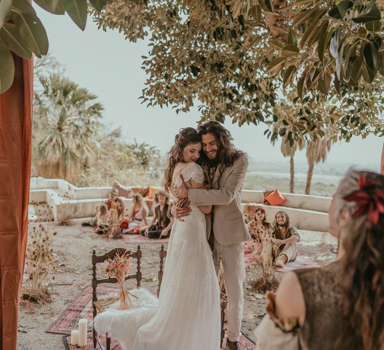 Bride & groom embrace outside after wedding ceremony as bride wears boho chic wedding gown