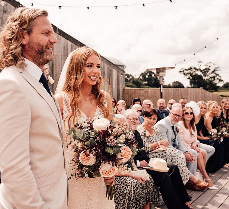 Bride clutches artificial wedding bouquet during ceremony