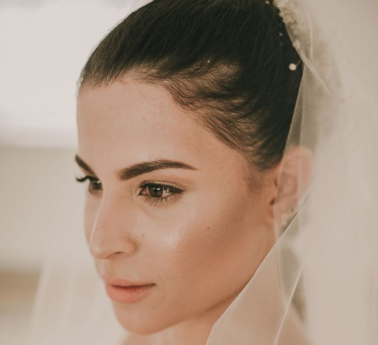 Bride with brown hair tied back in a bun with natural wedding makeup 