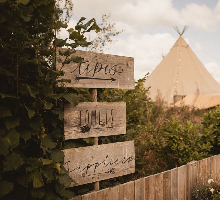 Wooden signs outside of tipis at Inkersall Grange Farm for summer wedding