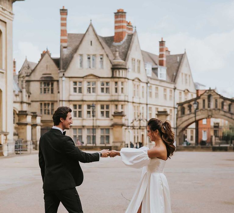 Bride with a high ponytail in a Nortier Shallow wedding dress with detachable sleeves in the courtyard at Bodleian Library 