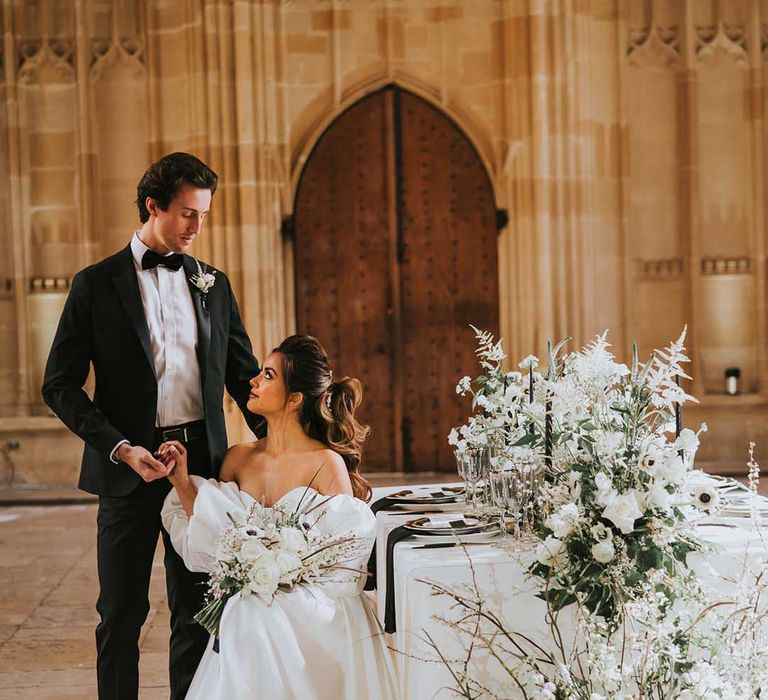 Bride in a Nortier Shallow wedding dress sitting at the intimate reception decorated with white flowers at Bodleian Library 