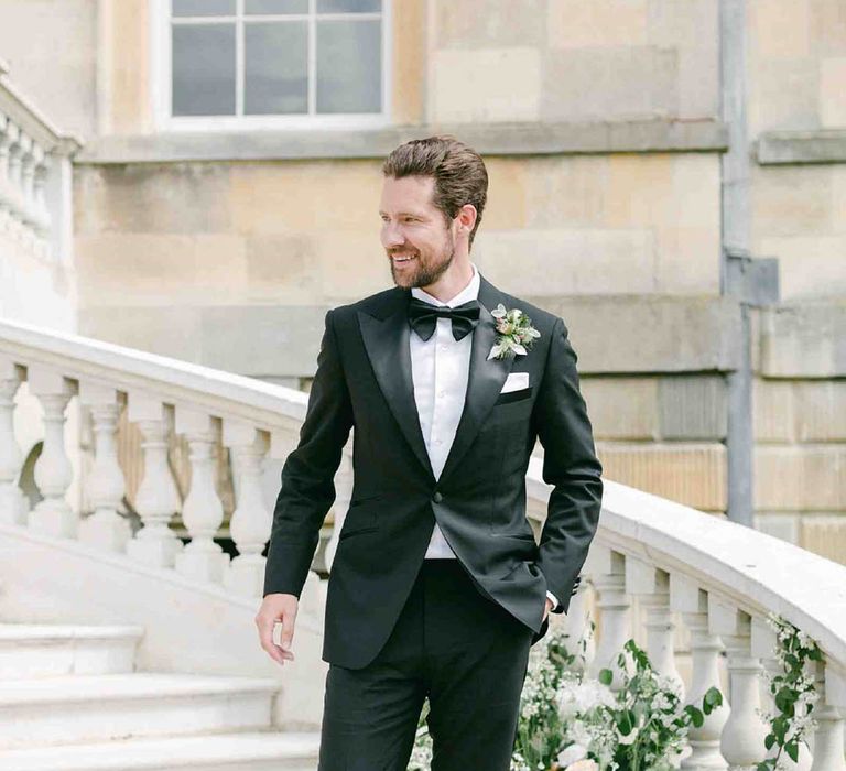 Stylish groom in a black tuxedo at country house wedding venue 