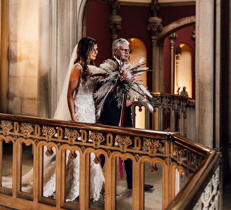 Bride stands with her father on balcony on her wedding day