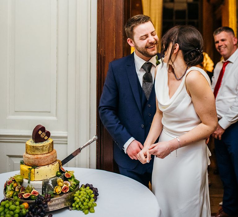 Bride & groom cut cheese tower in replacement of wedding cake