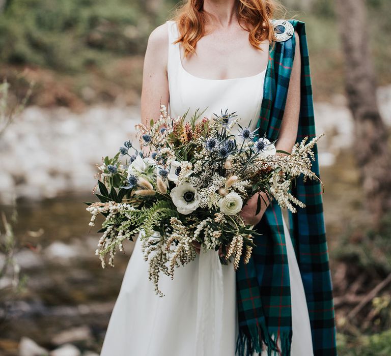 beautiful bride with red hair holding an anemone wedding bouquet with thistles and foliage 