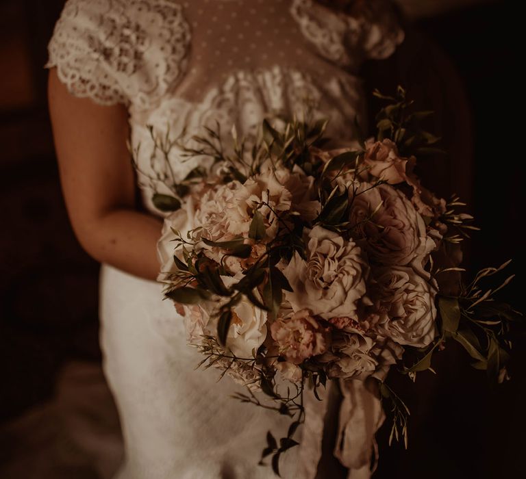 Bride in a lace wedding dress holding a romantic pink and white wedding bouquet 