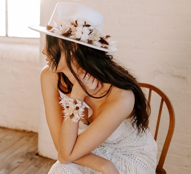 Boho bride in a strapless lace Shikoba Bride wedding dress in a fedora hat covered in dried flowers 