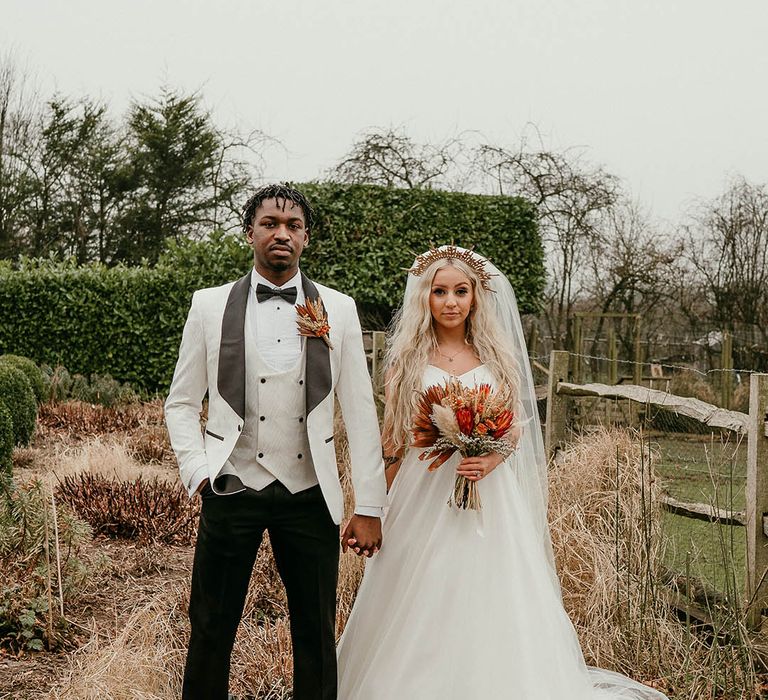 Bride and groom at modern winter wedding with orange decor and pampas grass detail