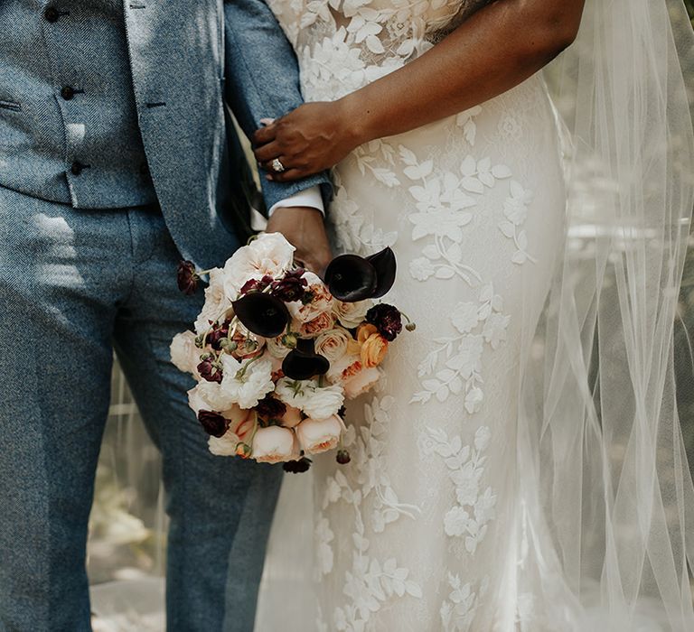 Wedding bouquet of white, pink, orange, dark red and black flowers in outdoor destination wedding