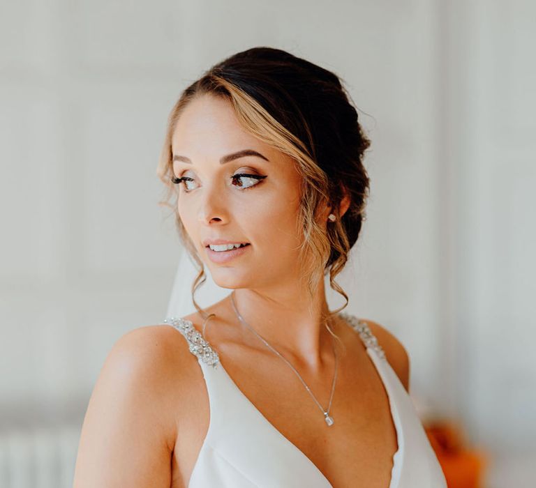 Bride in a Mobile wedding dress with deep V front, embellished straps and sparkling silver jewellery