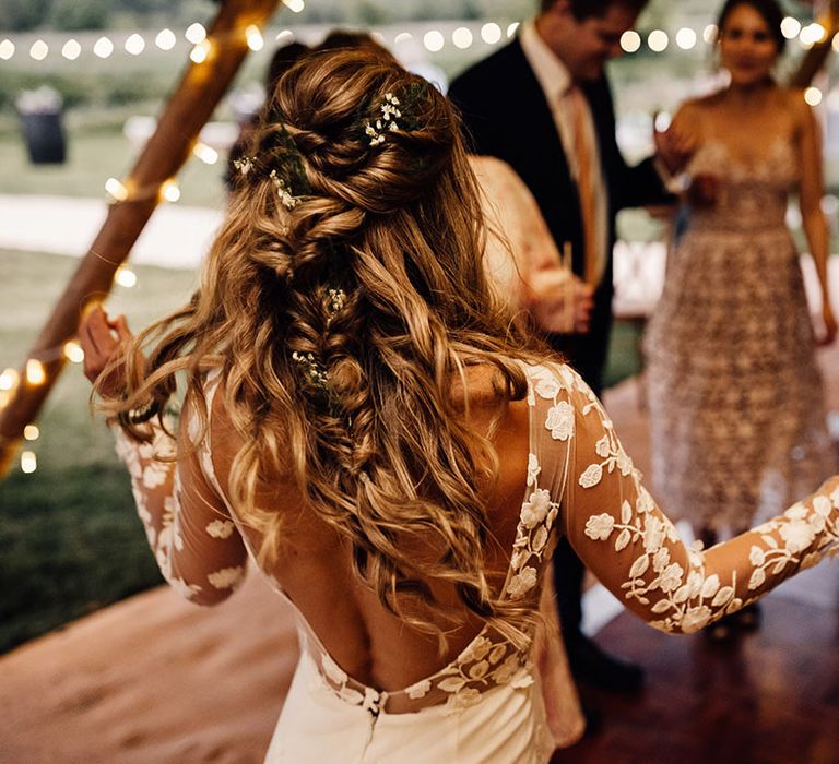 Bride with braided hairstyle and flowers braided in dances in lace wedding dress 