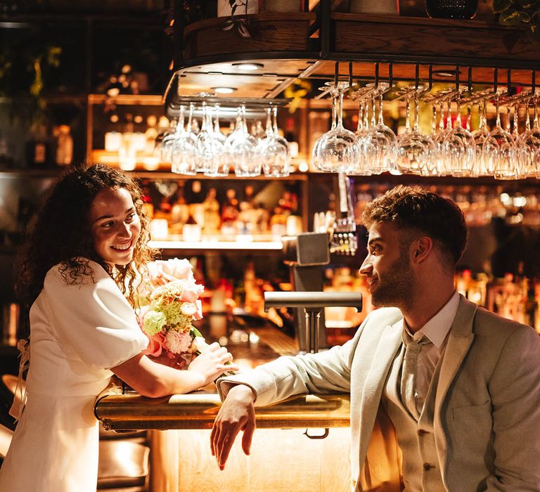 Urban wedding at Singer Tavern pub in Shoreditch, London with bride in a short wedding dress and groom in a pale green suit 