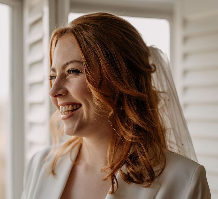 Bride wears her red hair in loose curls complete with veil to the back